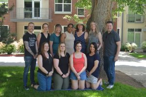 A group of 11 people posing for a photo outside in front of a tree. 